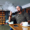 Young handsome bearded man sitting in a café, enjoying a casual moment with a drink and smartphone